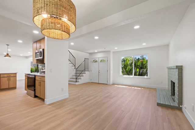 Empty living room with a brick fireplace and a staircase