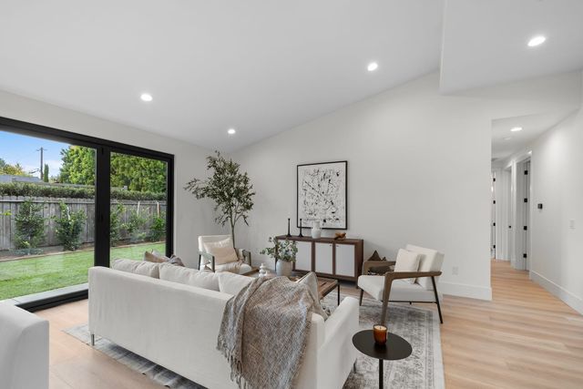 Living room with a white sofa and black-framed glass doors to a fenced yard
