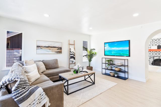 Open living room with a sectional sofa, a coffee table and an arched opening to the next room