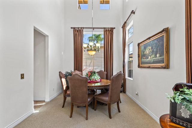 Dining room with a round table, upholstered chairs and a framed painting