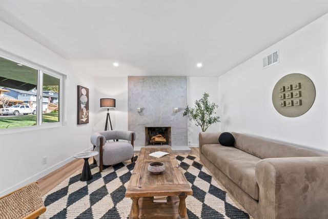 Living room with a stone fireplace, a long sofa and a patterned rug