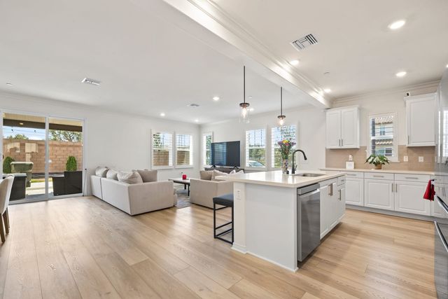 Open living room and white kitchen with an island and sliding doors to the patio