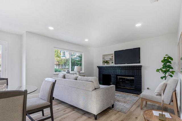 Living room with a black brick fireplace, a sofa and a dining table by the window