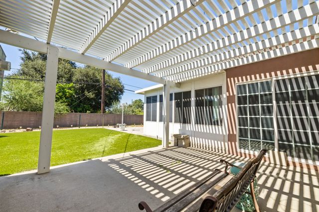 Covered patio with a lattice roof behind an older single-story home