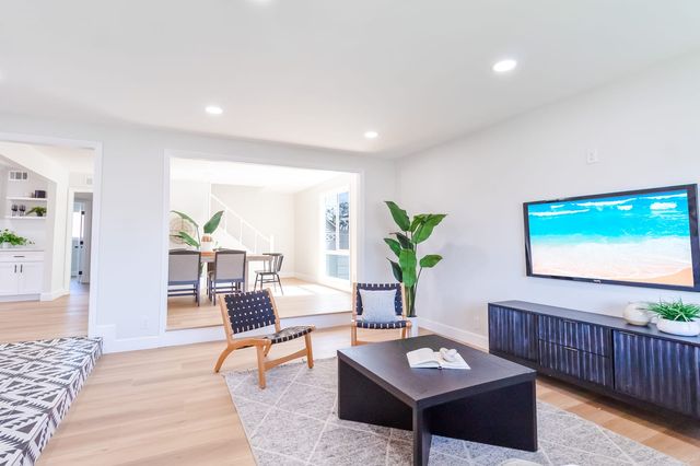 Living room with a long low media console, two woven chairs and a view through to the dining area