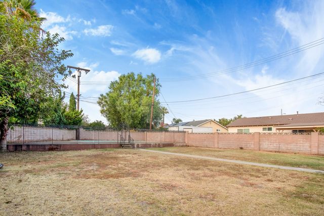 Back yard bounded by a block wall, with neighboring roofs beyond