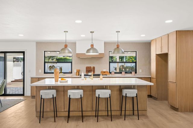 Kitchen with a long island, three pendant lights and wood cabinetry
